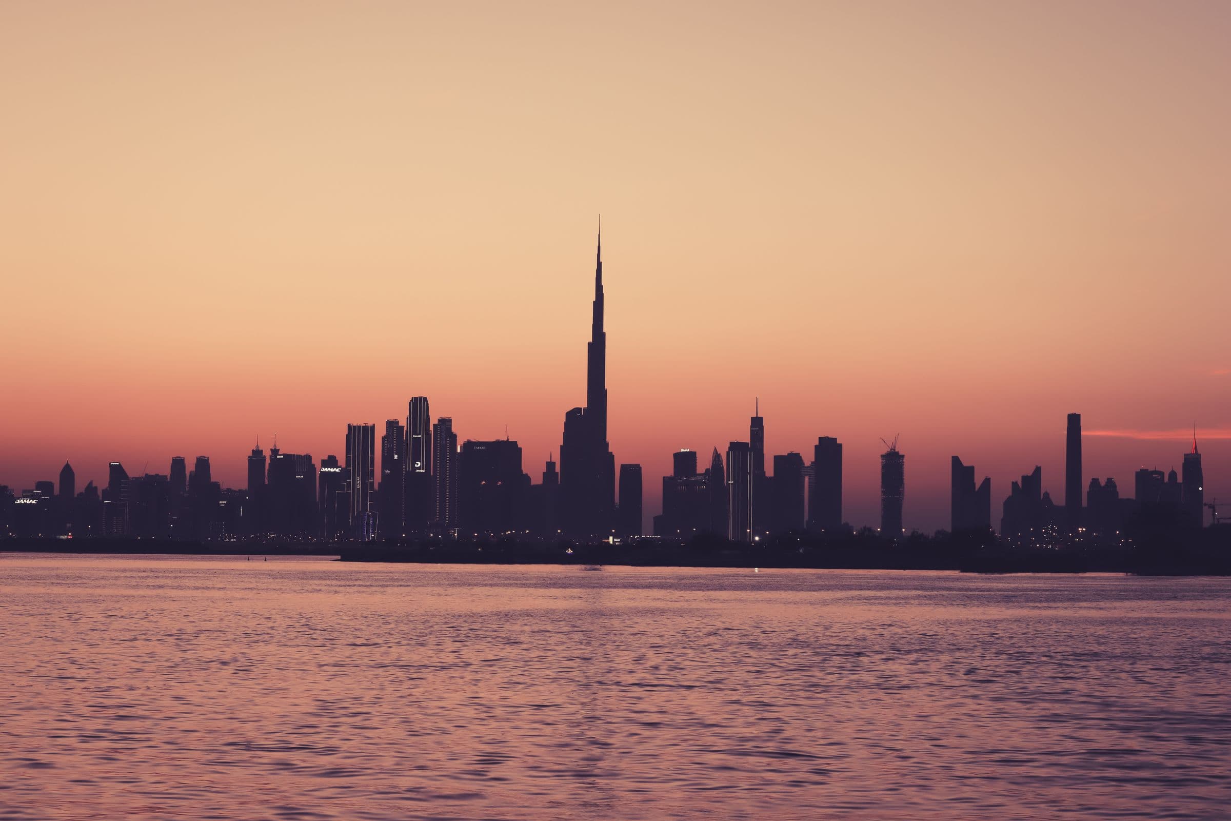 Dubai skyline silhouetted across the water at dusk